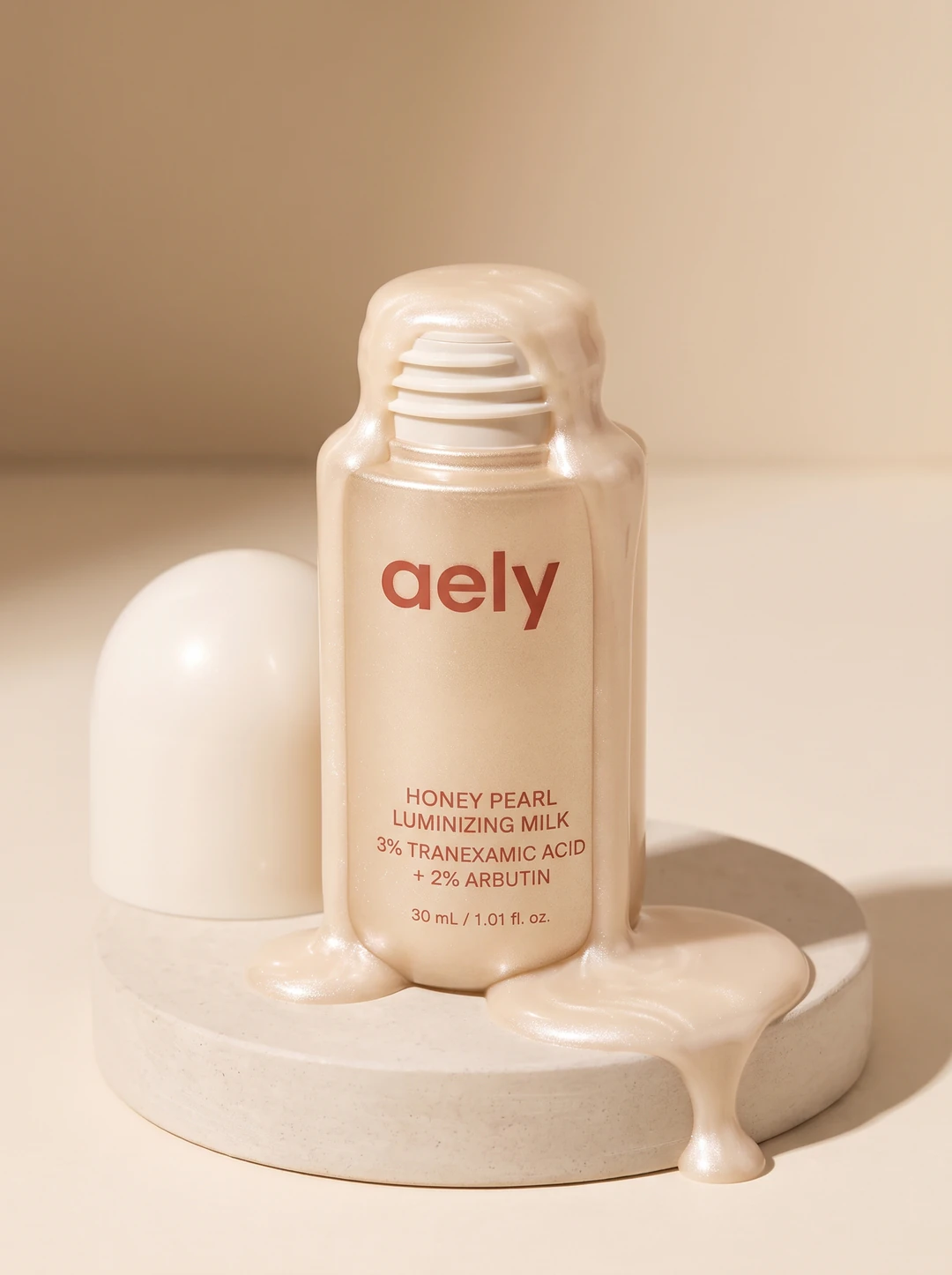 Honey Pearl Luminizing Milk, the bottle uncapped with pearlescent milk welling out of the open neck and pooling on the plinth